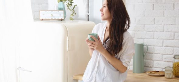 Kvinna dricker sitt morgonkaffe i lugn och ro i köket